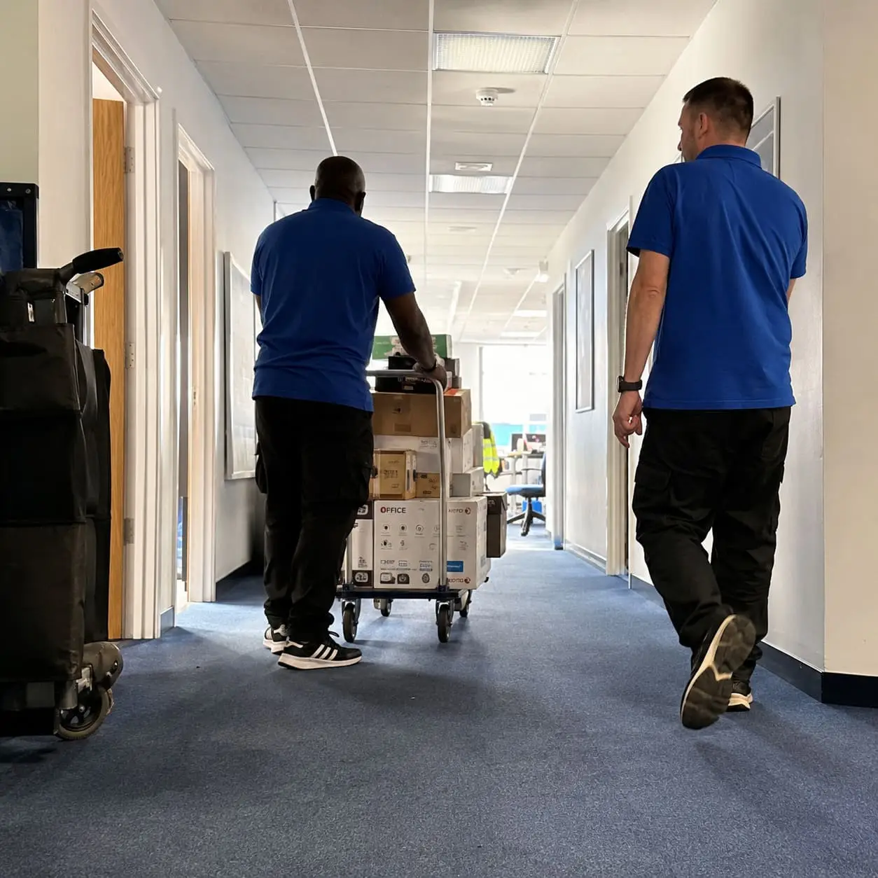 Office relocation team moving supplies through workplace corridor – Office Removal Service