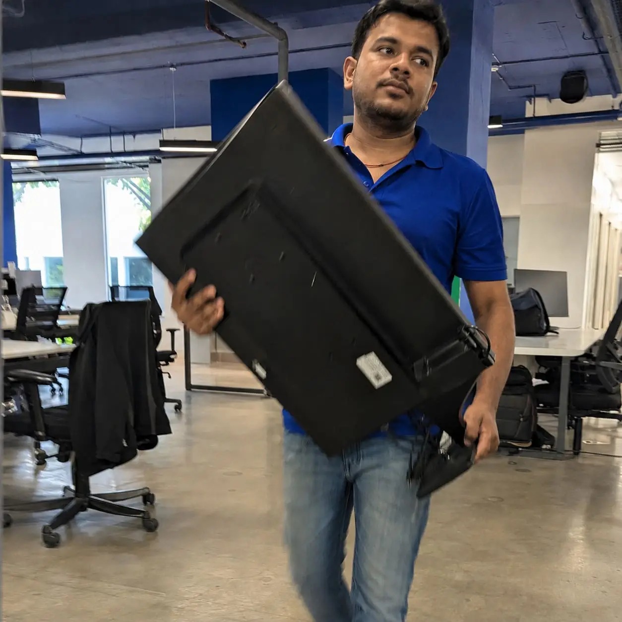 Office removal staff carrying computer monitor through modern workplace – Office Move Service
