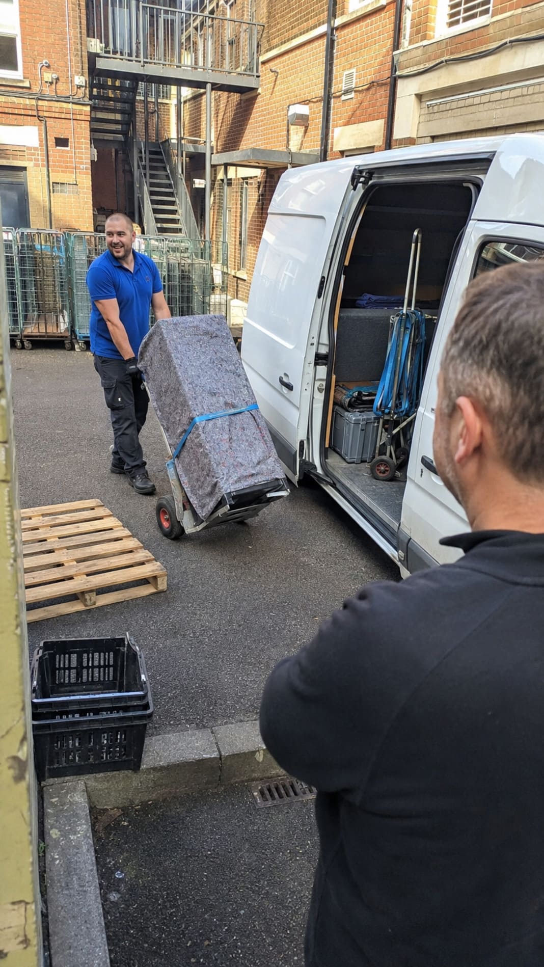 Man and van worker collecting appliance from commercial loading area.