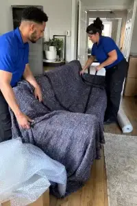 Wrapping a fabric sofa in thick protective moving blankets before loading it for a house move - Illustrative Image