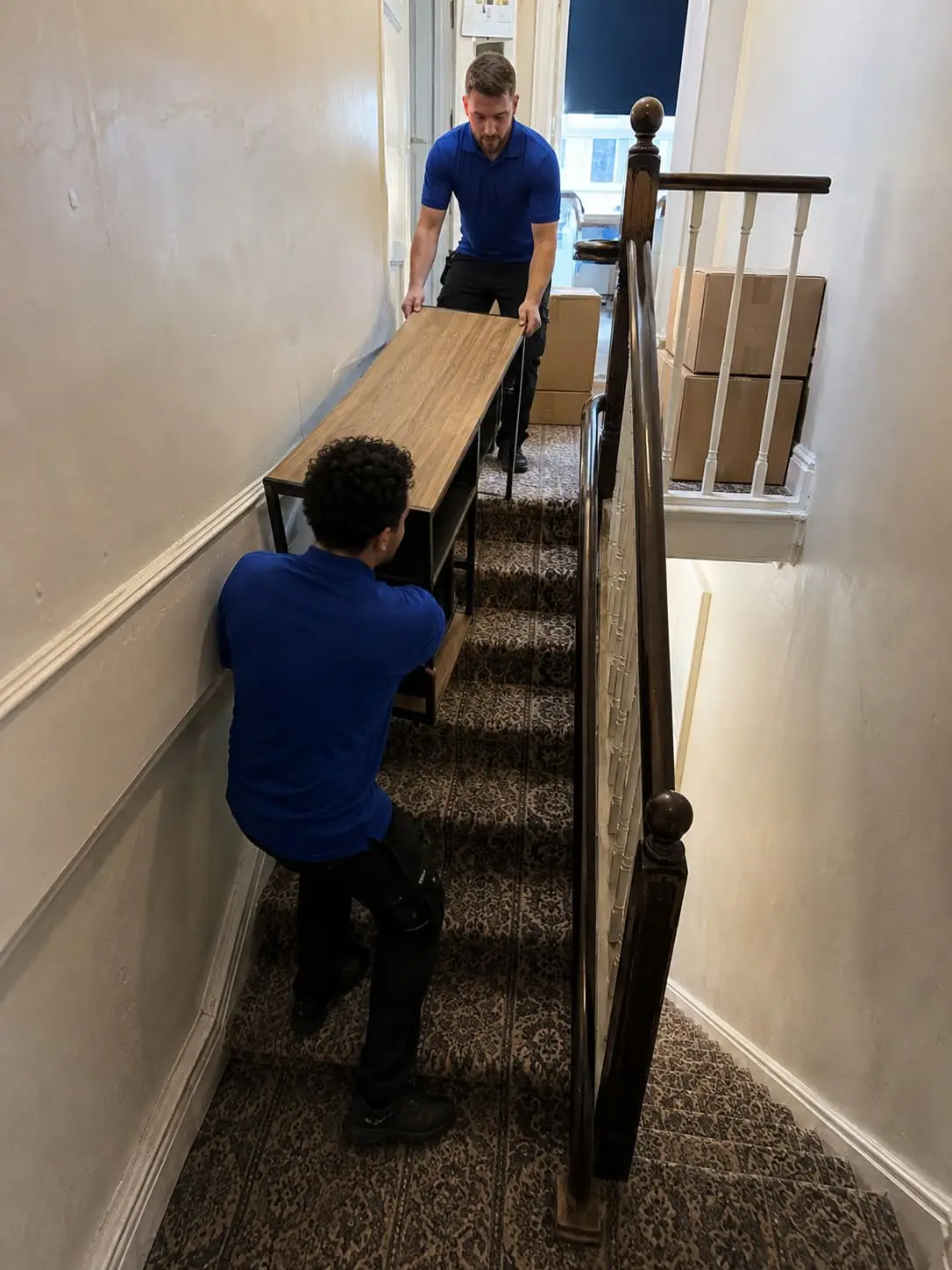 Student removal crew carrying furniture down narrow London stairs - Illustrative Image